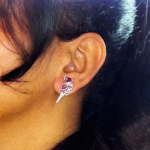 Silver peacock-shaped earrings adorned with ruby and clear gemstones, showcasing an elegant bird design with vivid red accents. From Trenzify Store.