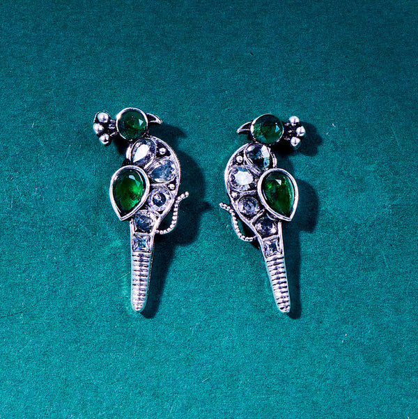 Silver peacock-shaped earrings featuring intricate green and clear gemstone details, with a stylized bird design. From Trenzify Store.