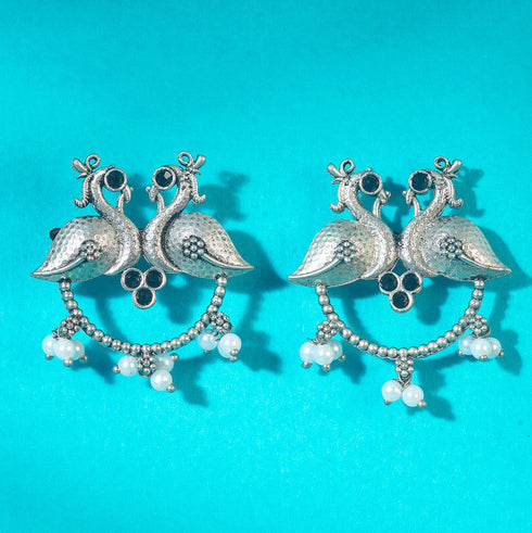 Antique-style silver peacock earrings adorned with black stones and white pearl danglers, combining tradition with bold elegance. Trenzify Store