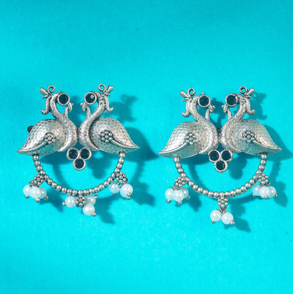 Antique-style silver peacock earrings adorned with black stones and white pearl danglers, combining tradition with bold elegance. Trenzify Store