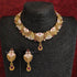 Rajwadi antique gold-plated Meenakari necklace set with ruby stones and matching earrings on red background.