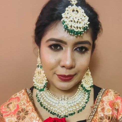 Bride wearing a traditional Kundan bridal necklace set with green bead drops, gold-plated finish, and matching chandbali earrings and maang tikka, perfect for weddings and festive occasions from Trenzify Store.