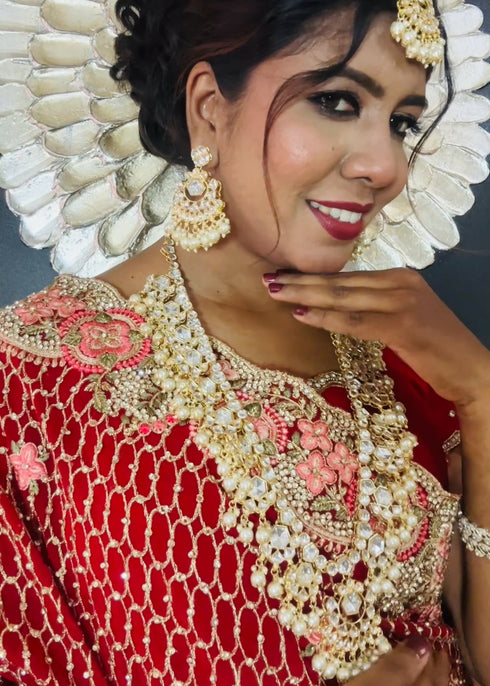 Indian bride wearing elegant Kundan bridal jewelry set with long necklace, matching earrings , and maang tikka embellished with pearls and stones - Trenzify Store.