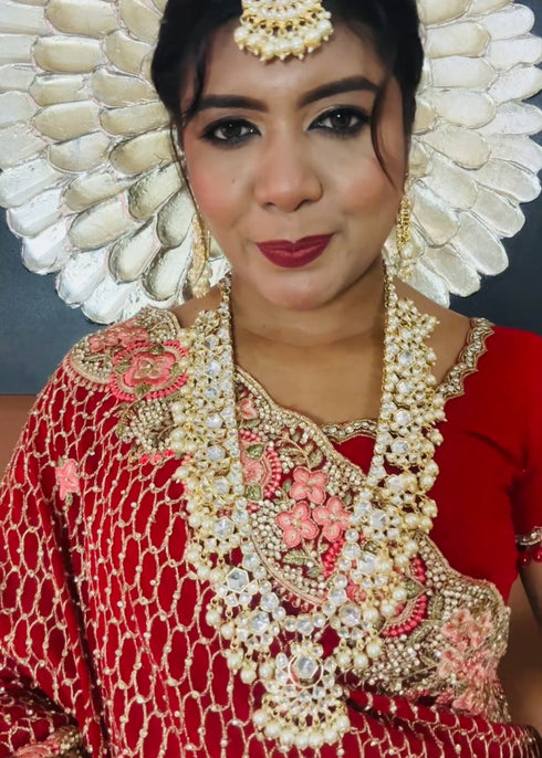 Indian bride wearing elegant Kundan bridal jewelry set with long necklace, matching earrings , and maang tikka embellished with pearls and stones - Trenzify Store.