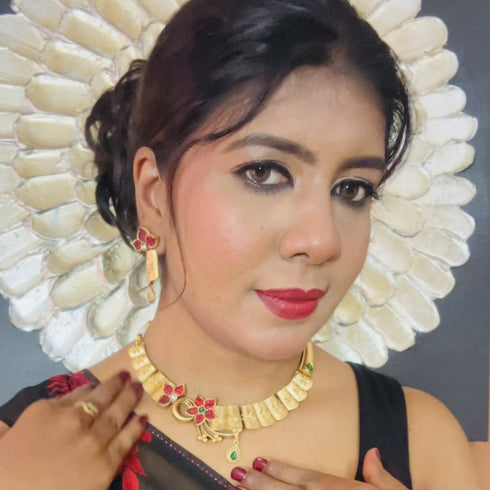 Model in black saree with red floral print wearing gold choker necklace set with red stones, matching drop earrings, and bracelet – imitation jewelry from Trenzify Store.