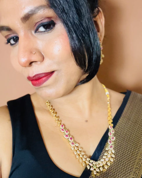 Model wearing American Diamond CZ necklace set with pink stones, green accents and gold plating – elegant floral jewelry with matching earrings, perfect for weddings and parties.