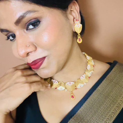 Rajwadi antique gold-plated Meenakari necklace set with ruby stones and matching earrings on red background.