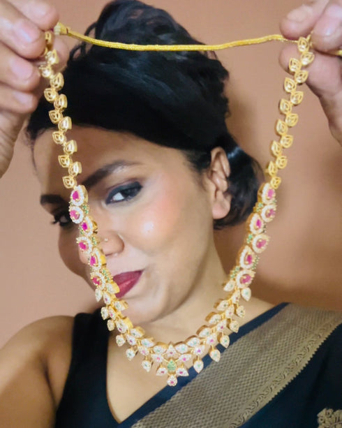 Model wearing American Diamond CZ necklace set with pink stones, green accents and gold plating – elegant floral jewelry with matching earrings, perfect for weddings and parties.