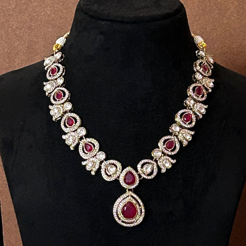 Elegant ruby red stone necklace set with matching drop earrings, featuring teardrop design, white CZ embellishments, and gold-plated finish – perfect for weddings and festive occasions.