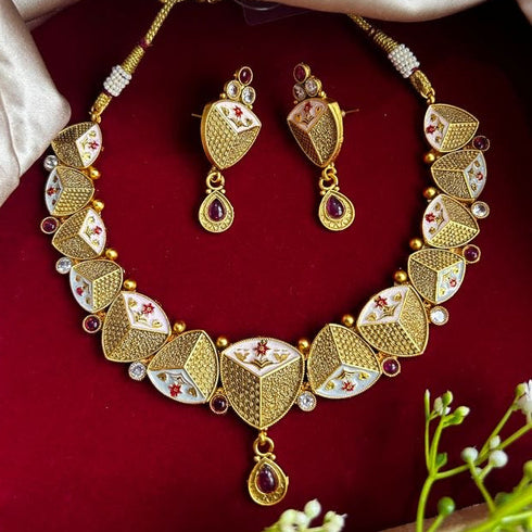 Rajwadi antique gold-plated Meenakari necklace set with ruby stones and matching earrings on red background.