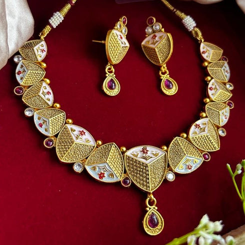 Rajwadi antique gold-plated Meenakari necklace set with ruby stones and matching earrings on red background.