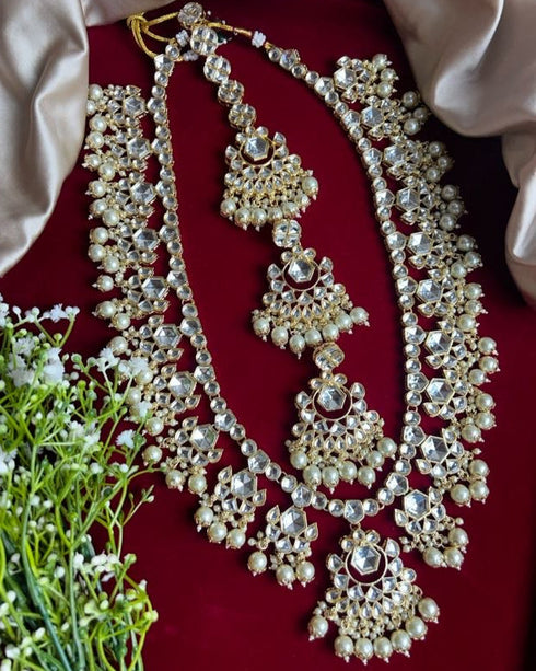 Traditional Kundan bridal jewelry set with long necklace, matching earrings , and maang tikka embellished with pearls and stones - Trenzify Store.