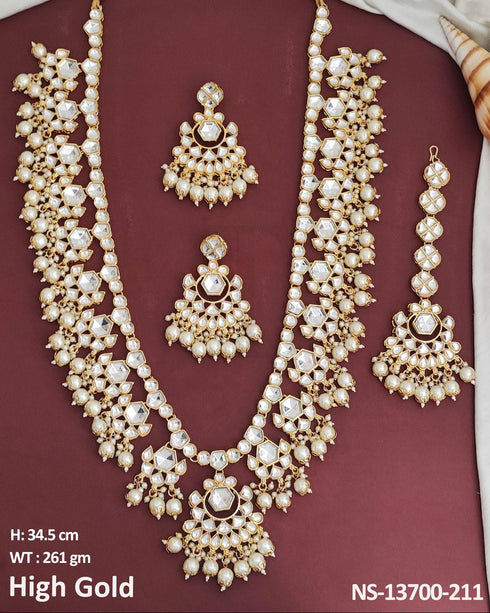 Indian bride wearing elegant Kundan bridal jewelry set with long necklace, matching earrings , and maang tikka embellished with pearls and stones - Trenzify Store.