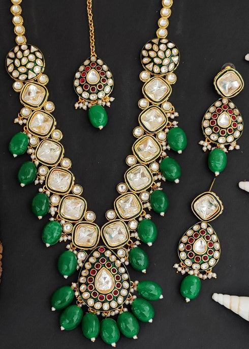 Gold plated Kundan necklace set with green stones, red enamel accents, pearls and matching earrings and maang tikka – traditional bridal jewelry from Trenzify Store.